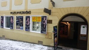 A museum with a sign reading "MUSEUM VLTAVINO" and several posters advertising jewelry and seasonal clearance. - Residence Muzeum Vltavinu (Cesky Krumlov)