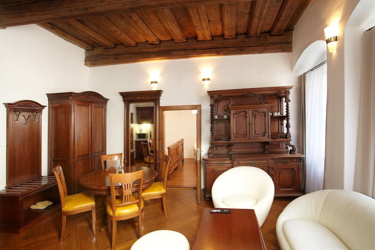A dining area with wooden furniture, a white sofa, and a kitchen visible through an open doorway.