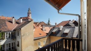 A balcony with a view of a town square, featuring historic buildings with red-tiled roofs and a prominent tower. - Residence Muzeum Vltavinu (Cesky Krumlov)