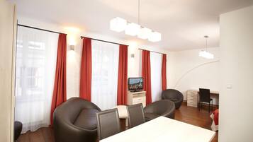 A modern room with a dining table, chairs, a TV, and a desk.