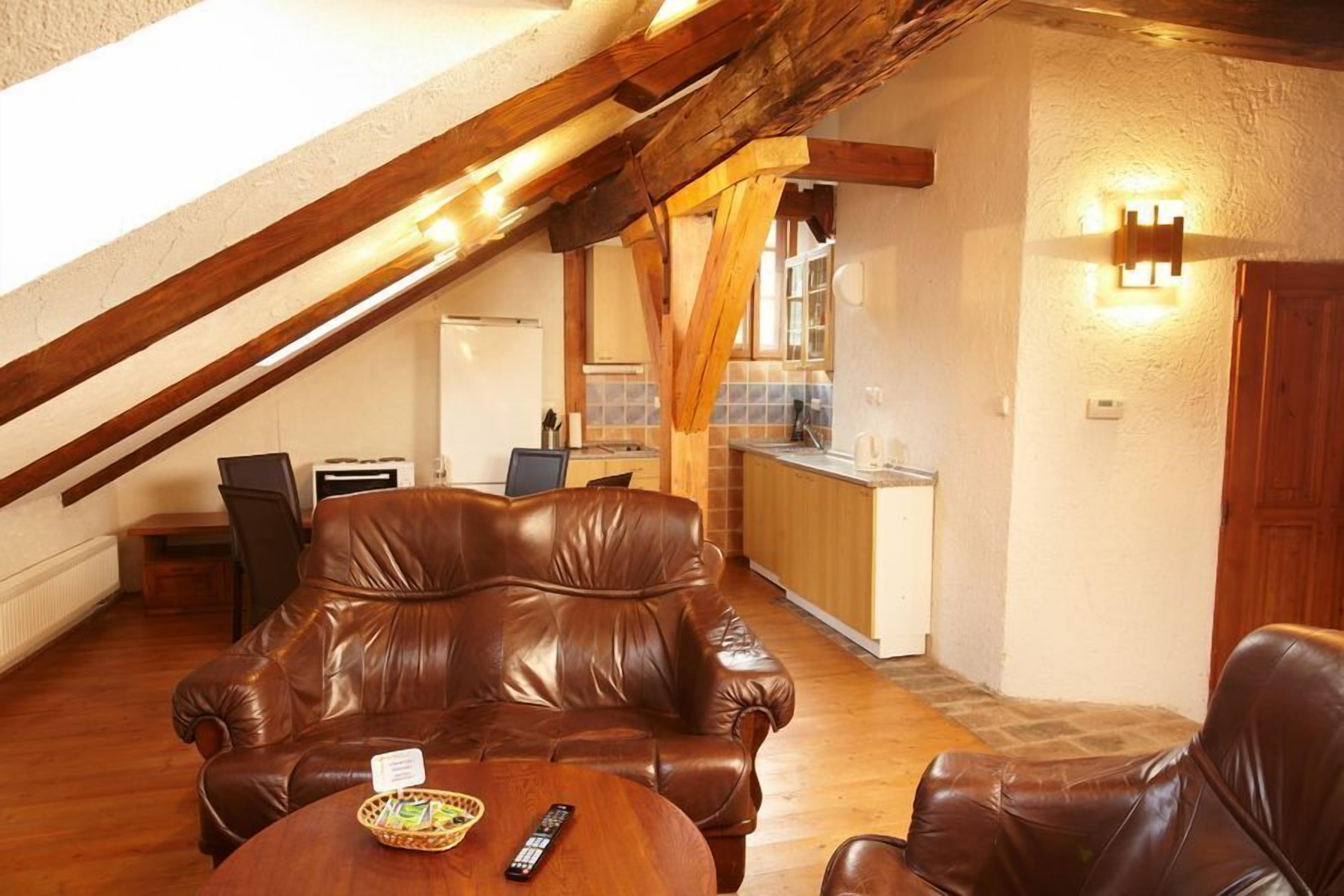 A cozy living room with a leather sofa, a wooden coffee table, and a kitchen in the background.