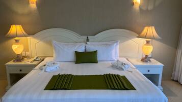 A neatly made bed with white linens, a green throw, and two bedside lamps.