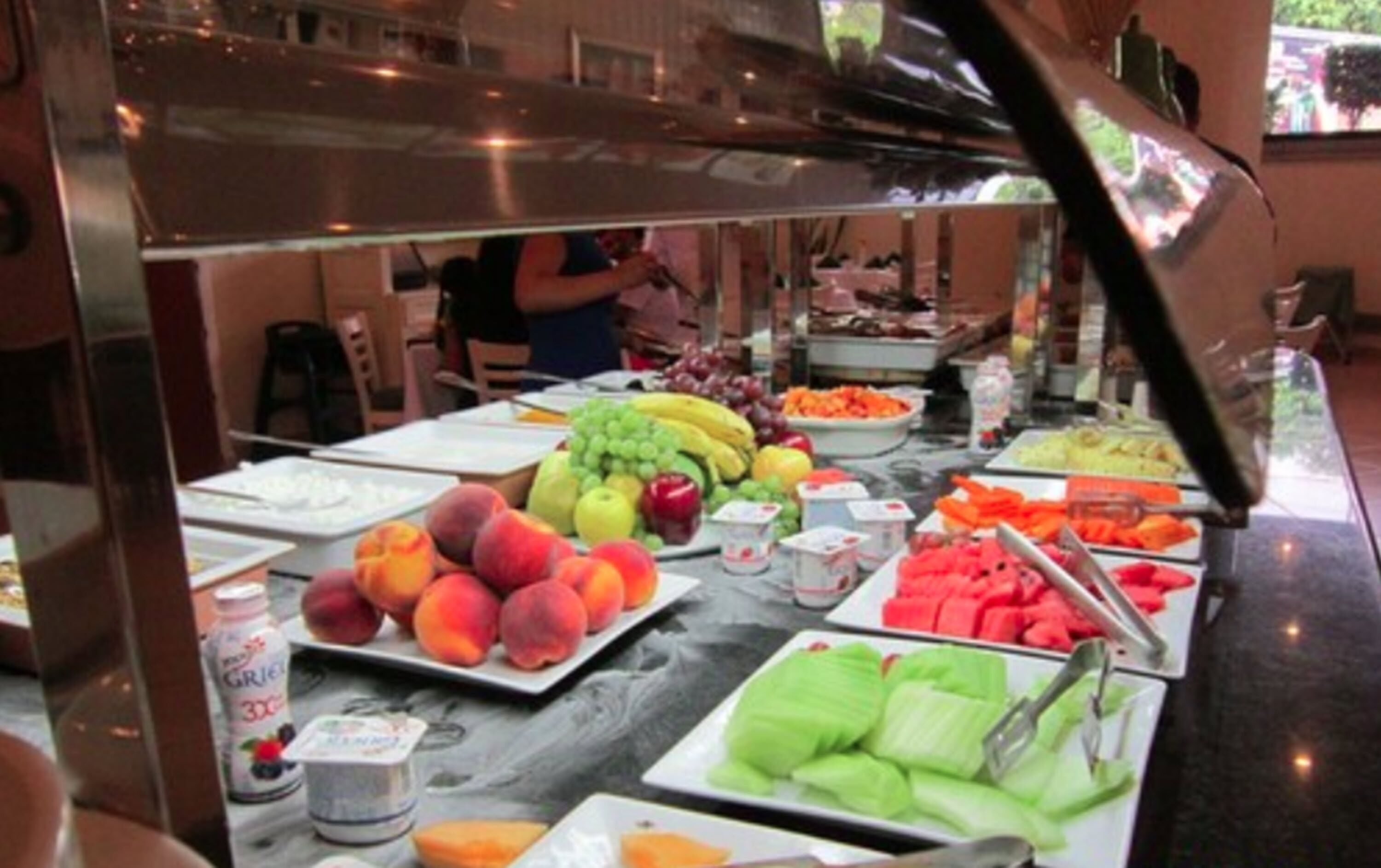 A buffet with various fruits and vegetables, including peaches, bananas, and watermelon.