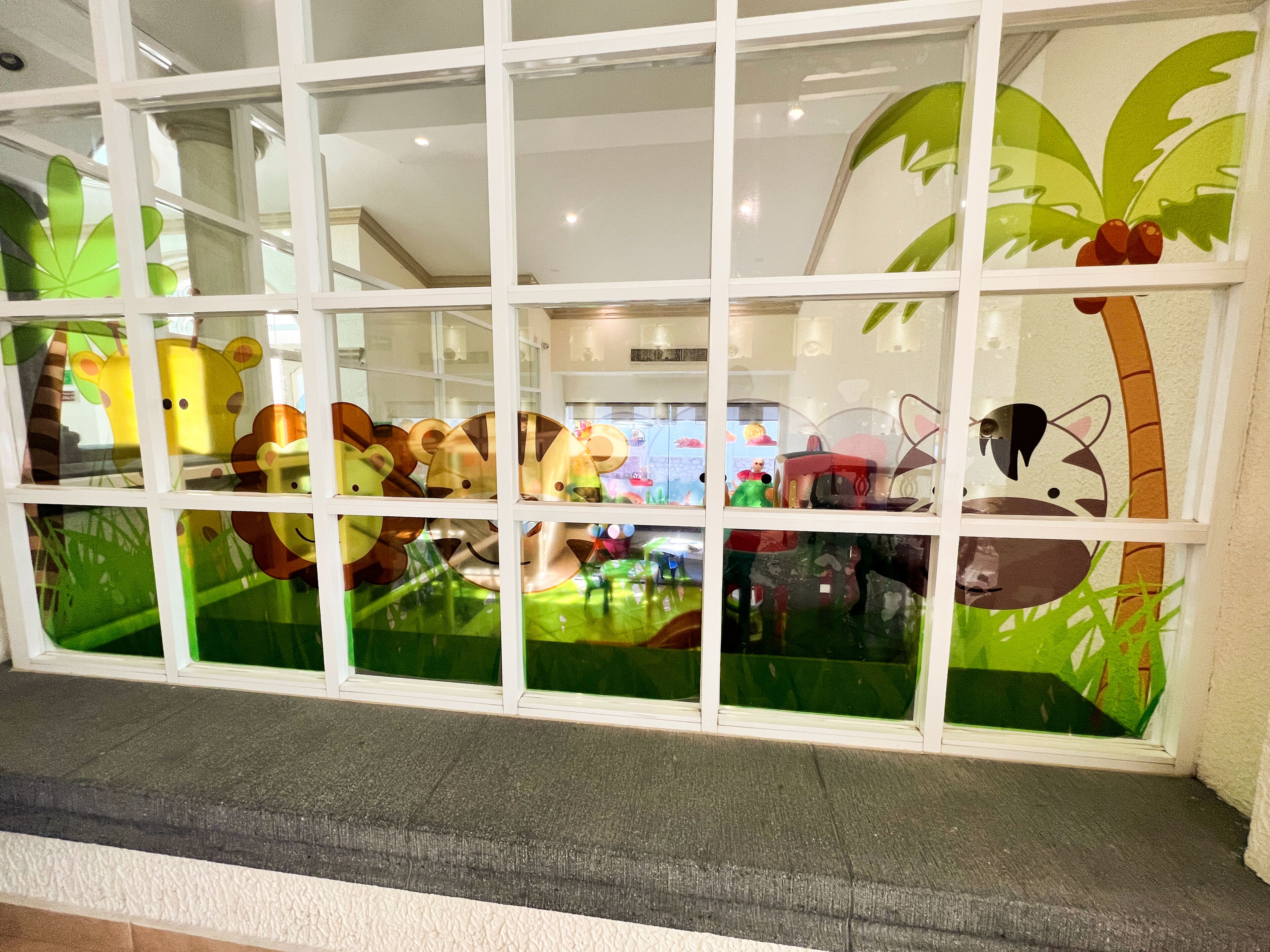A window with a view of a children's play area, featuring various toys and decorations.