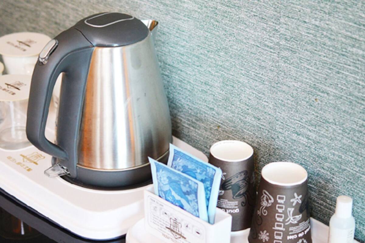 Una bandeja con una tetera, tazas de café y una tarjeta.
