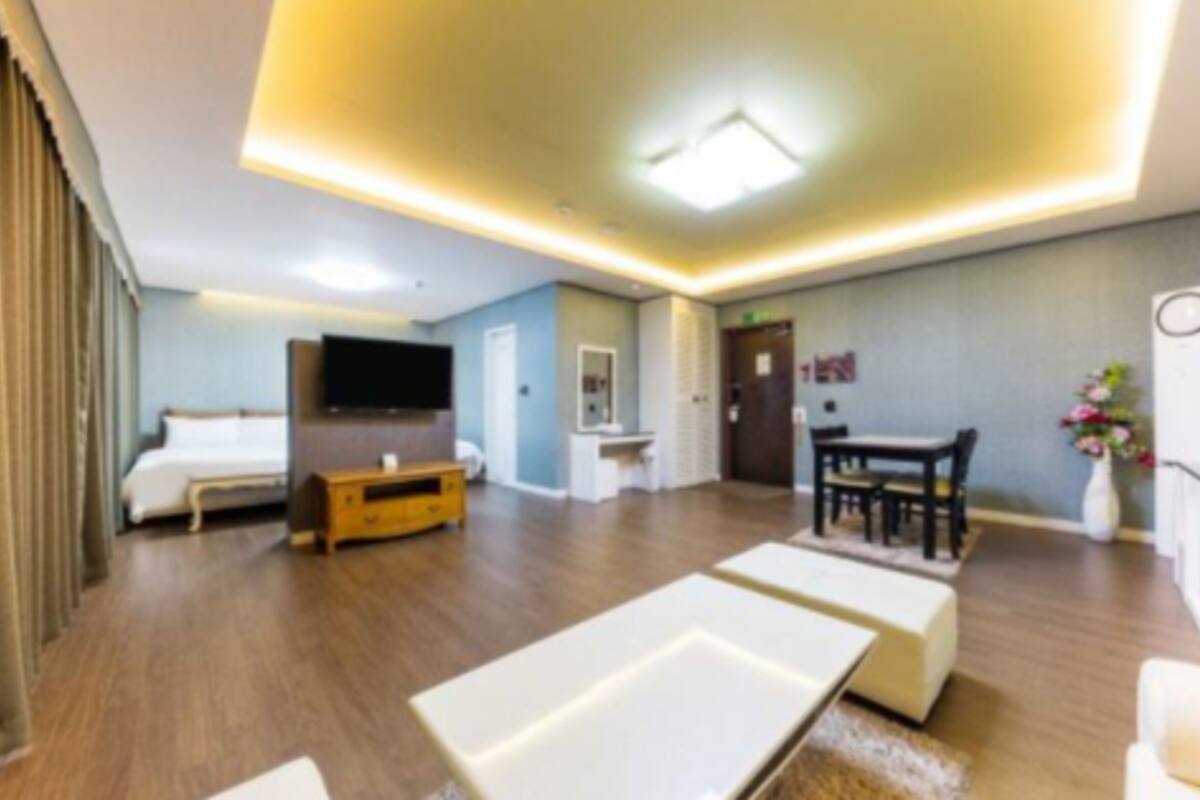 Una habitación de hotel moderna con cama, televisor, escritorio y zona de comedor.