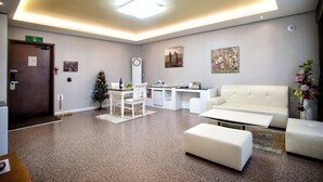 A modern hotel lobby with a reception desk, white sofas, a dining area, and a Christmas tree. - BENIKEA Technovalley Hotel (Daejeon)