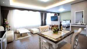 A hotel room with a bed, a desk, a dining table, and a TV. - BENIKEA Technovalley Hotel (Daejeon)