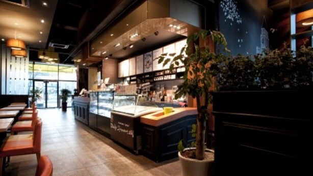 A restaurant interior with a counter, seating area, and potted plants. - BENIKEA Technovalley Hotel (Daejeon)