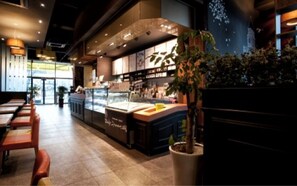 A restaurant interior with a counter, seating area, and potted plants. - BENIKEA Technovalley Hotel (Daejeon)