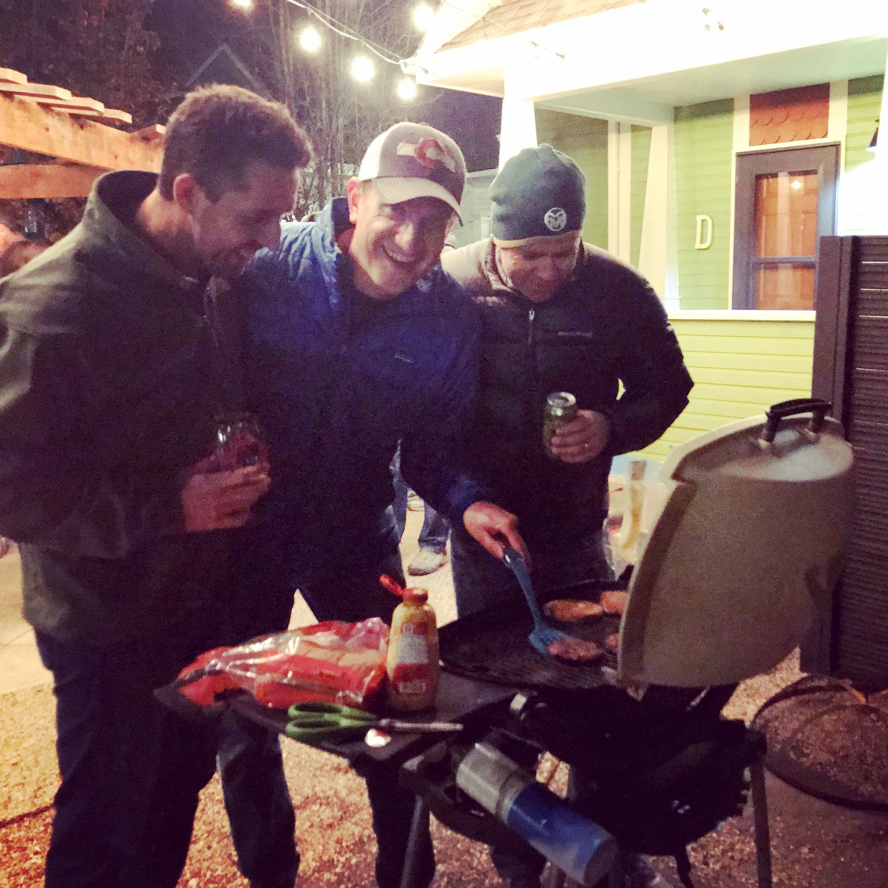 Un gruppo di persone all'aperto di notte, che prepara cibo su una griglia.