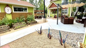 A patio area with raised garden beds, outdoor furniture, and a clock on a building. - Remington Flats Hotel (Fort Collins)