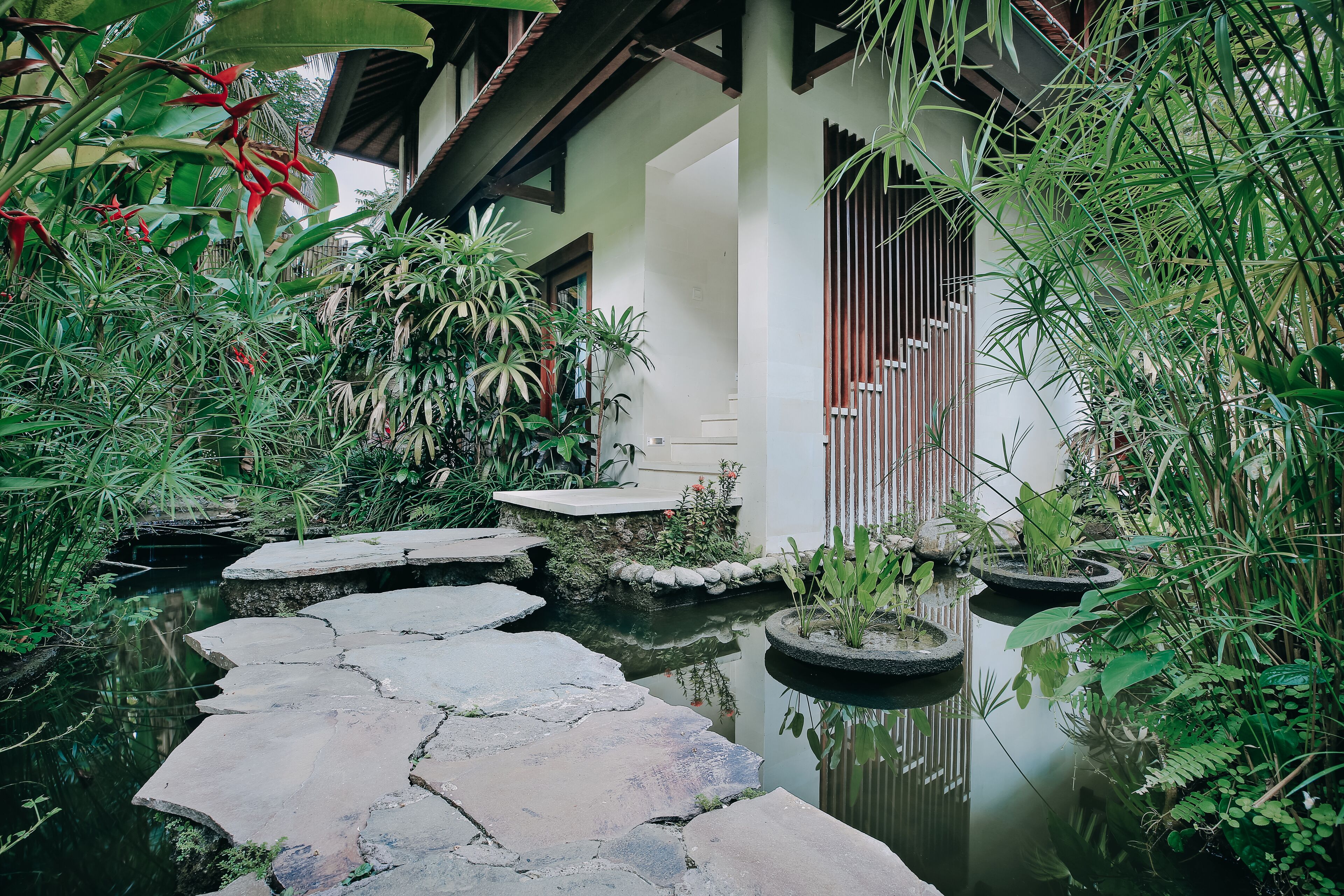 A tranquil garden with a stone pathway leading to a building with a traditional design.
