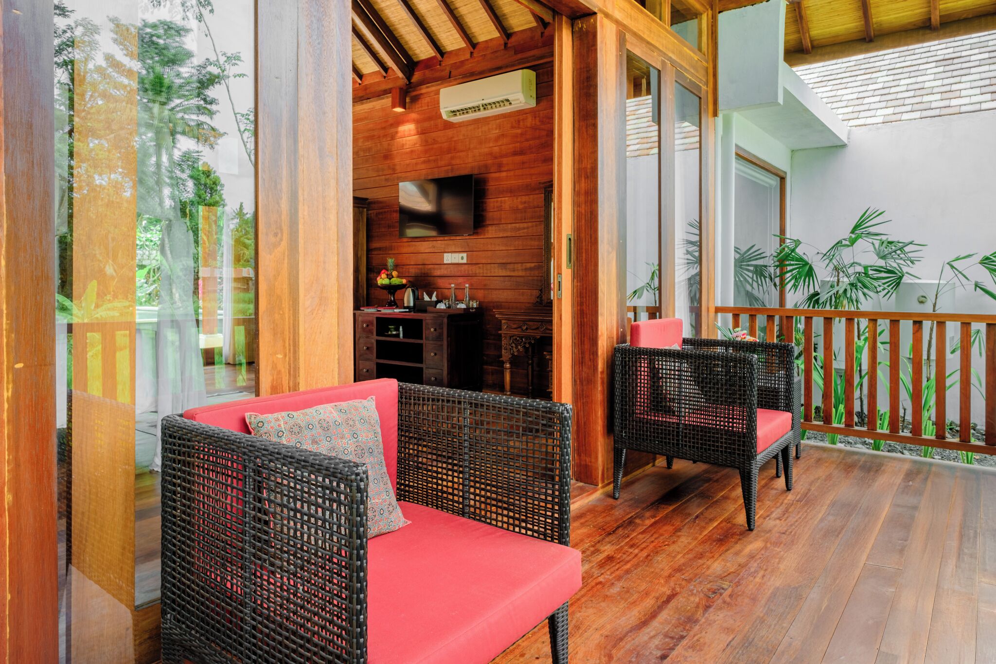 A wooden deck with wicker furniture and a red sofa.