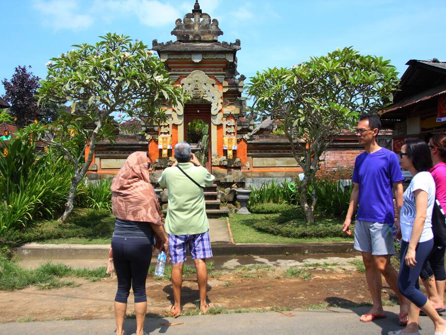 A temple with a traditional architectural style, surrounded by greenery and a paved walkway.