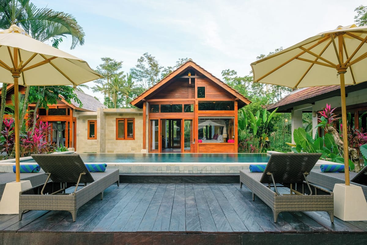 Une maison en bois à deux étages avec une piscine devant.