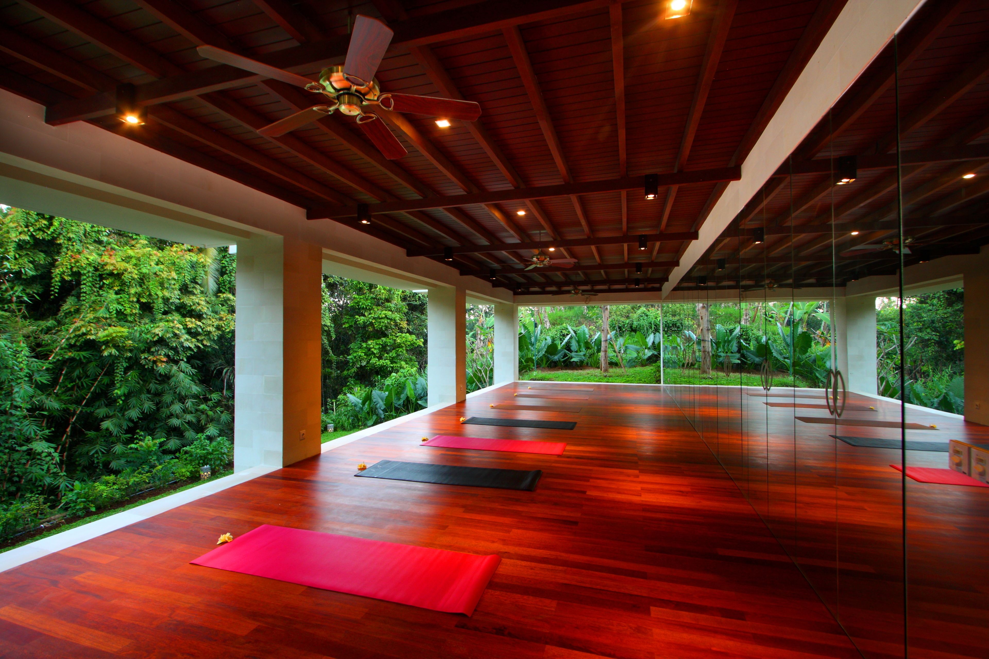 A spacious room with a wooden floor, large windows, and a ceiling fan.