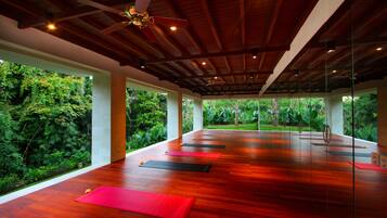A spacious room with a wooden floor, large windows, and a ceiling fan.