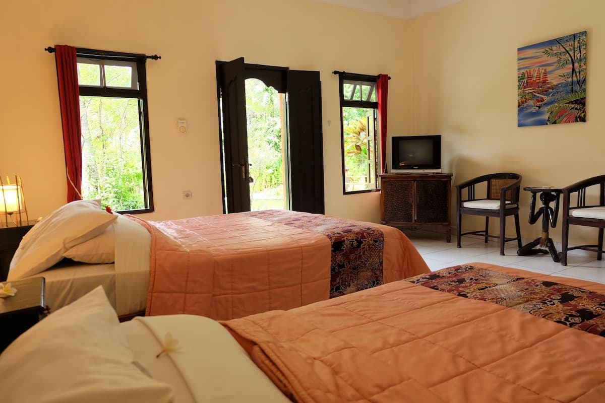 Une chambre d’hôtel avec deux lits, une télévision, un bureau et des chaises.