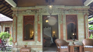 Una entrada ornamentada con diseño tradicional, un área de descanso con muebles de mimbre y una planta en maceta.