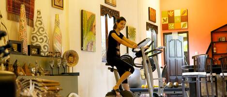 Una habitación con una cinta de correr, equipo de ejercicio y elementos decorativos.