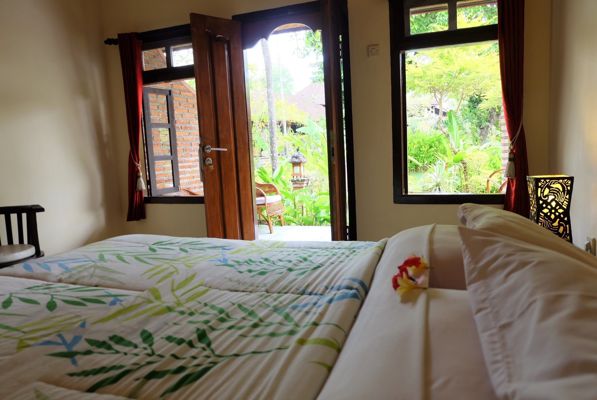 A room with a bed, a chair, and two windows.