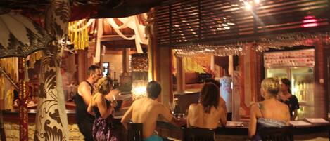 Un restaurante de temática tropical, con techo de paja y mobiliario de madera.