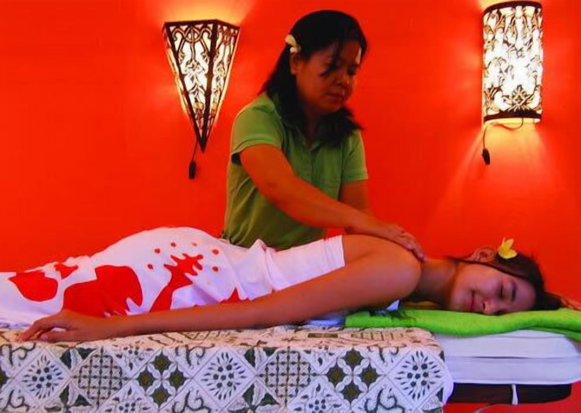 A massage therapy session in a room with a red wall and patterned floor.