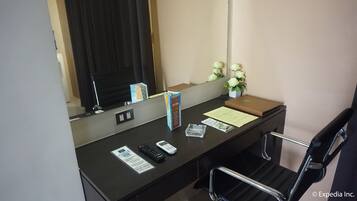 Un comptoir d’accueil d’hôtel avec un ordinateur, un téléphone, une petite plante et une boîte étiquetée « Noël ».
