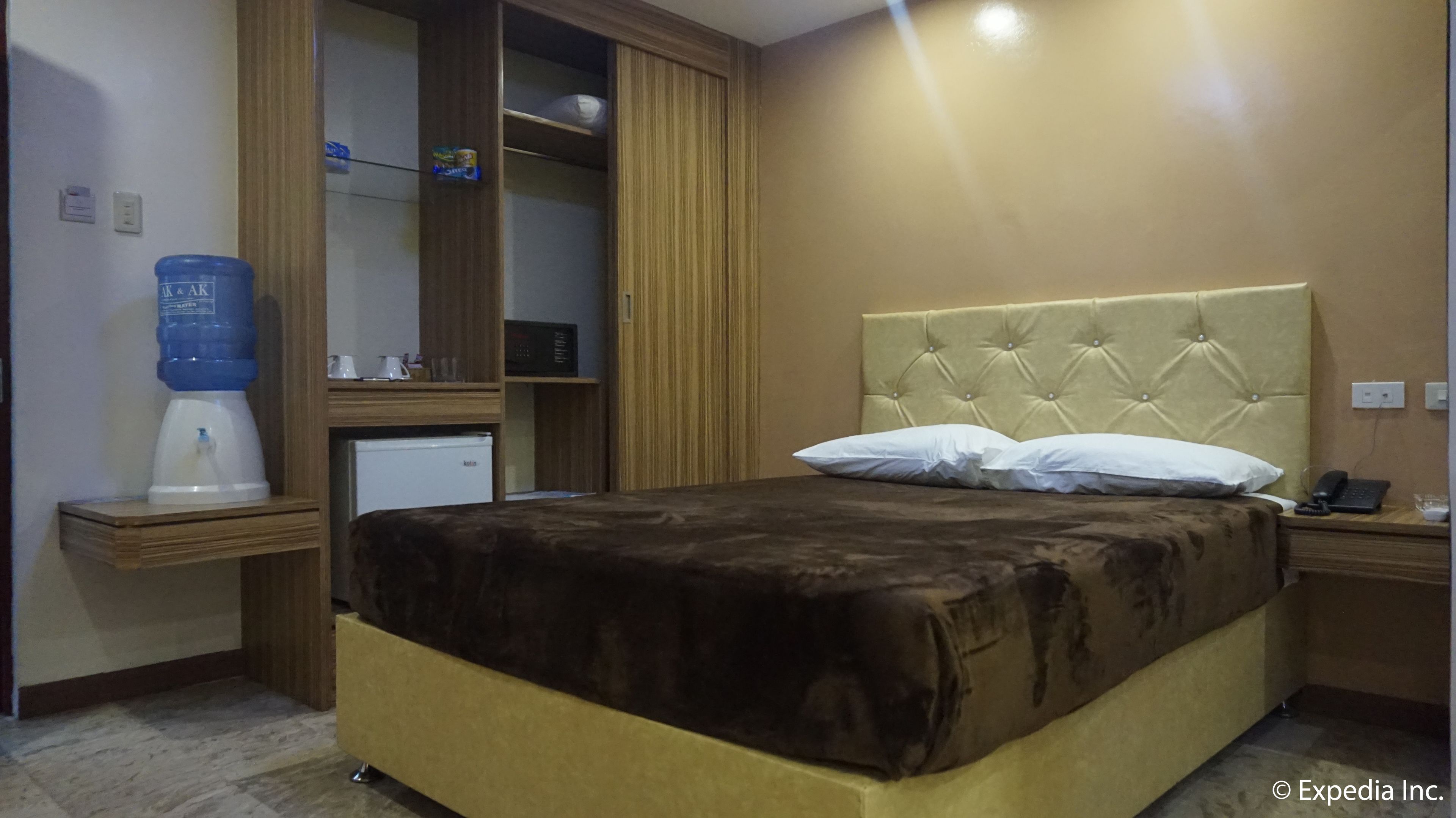 Une chambre d’hôtel équipée d’un lit, d’un minibar, d’un distributeur d’eau, d’un bureau et d’un téléphone.