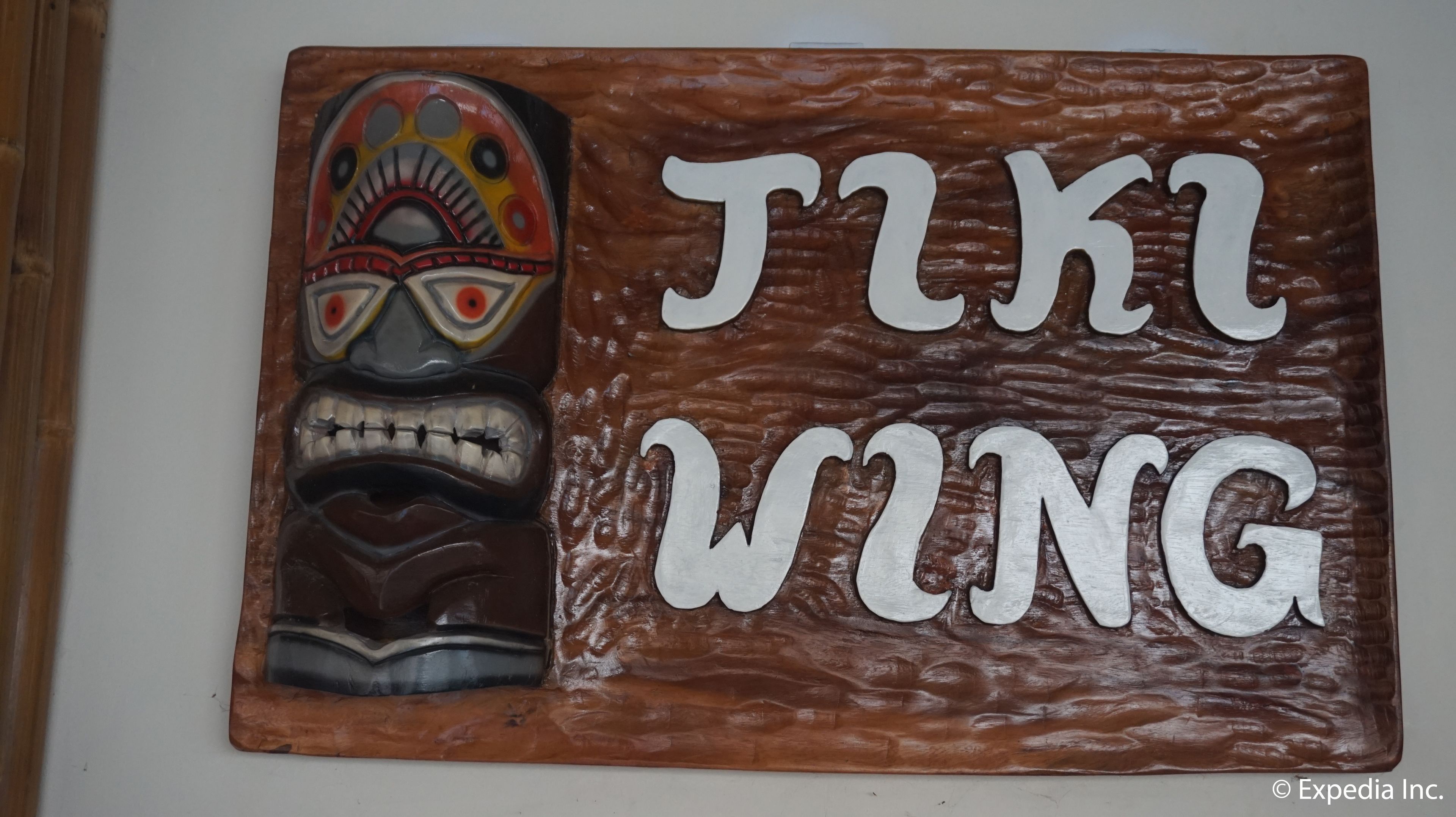 A wooden plaque with a carved totem and the text "TIKI WING".