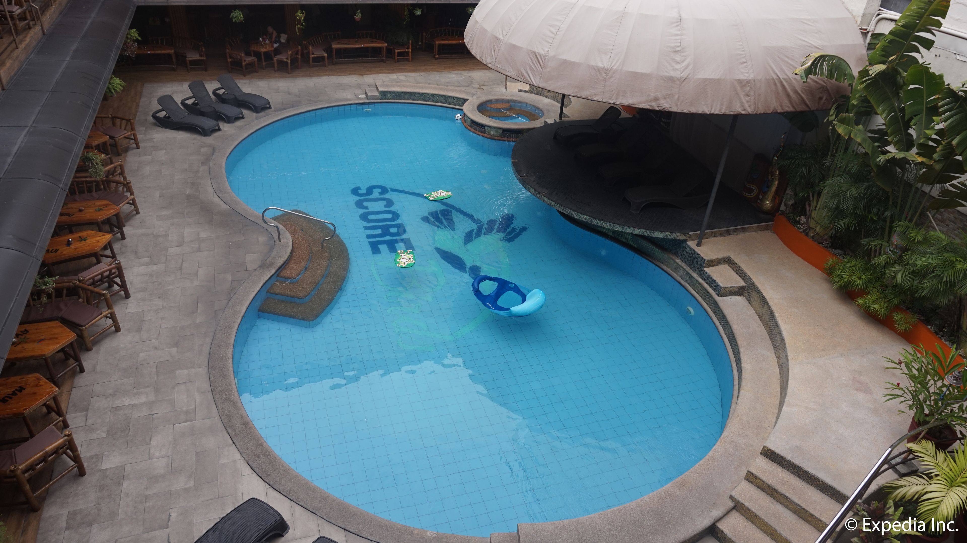 A swimming pool with a slide, lounge chairs, and tables around the pool area.