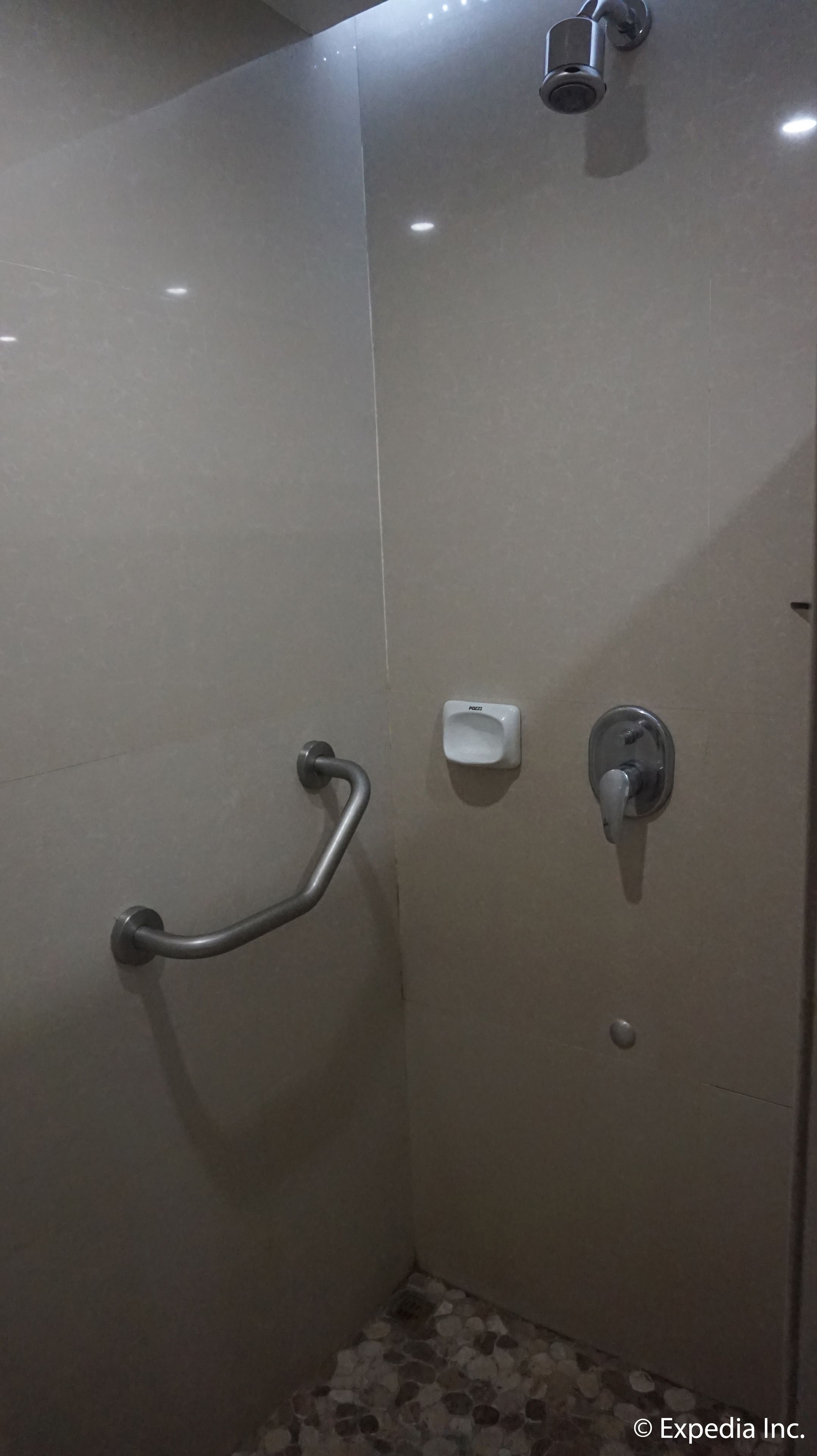 Una cabina de ducha con baranda, dispensador de jabón y grifo.