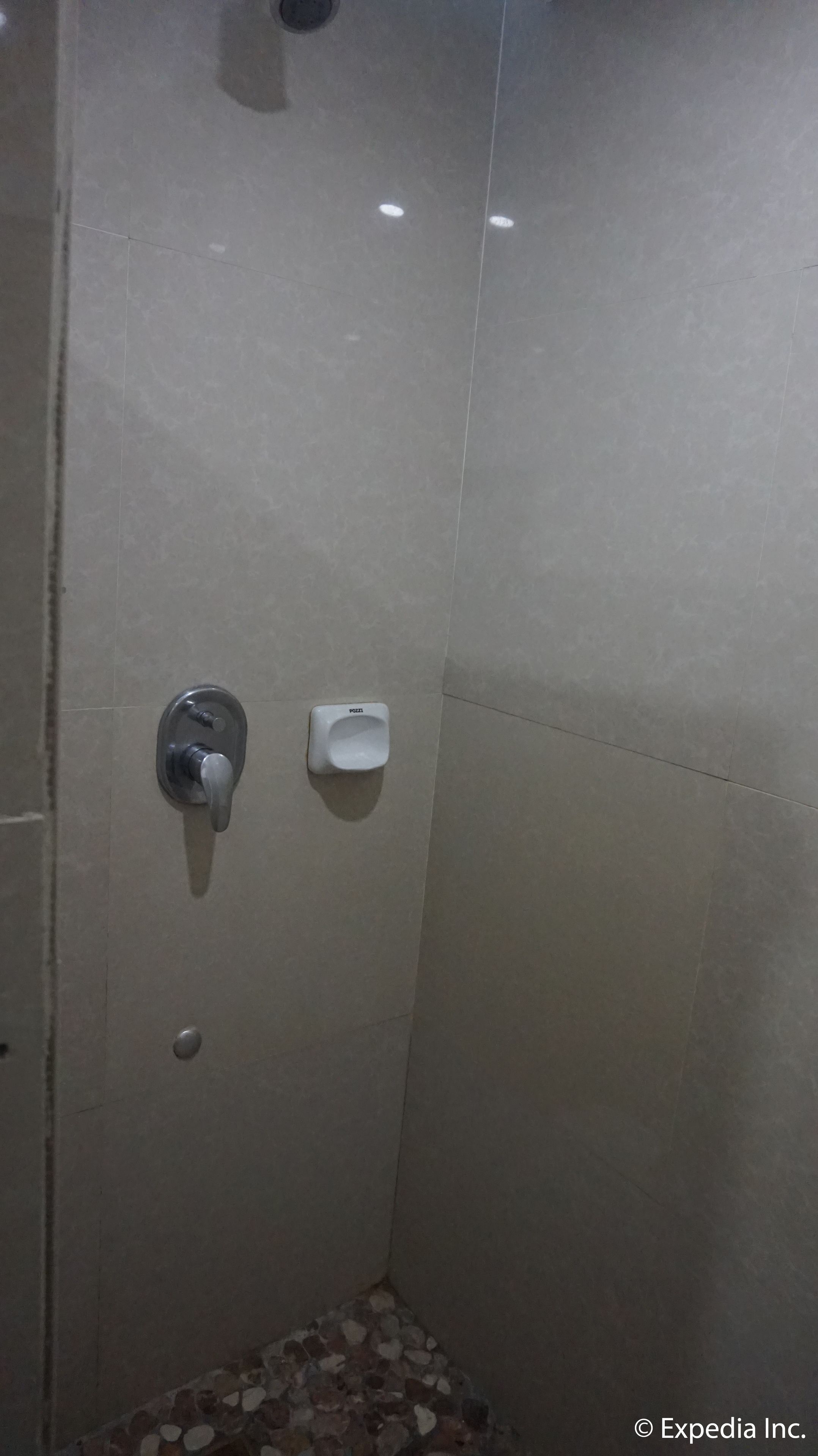 Una ducha con dispensador de jabón en la pared y un grifo.