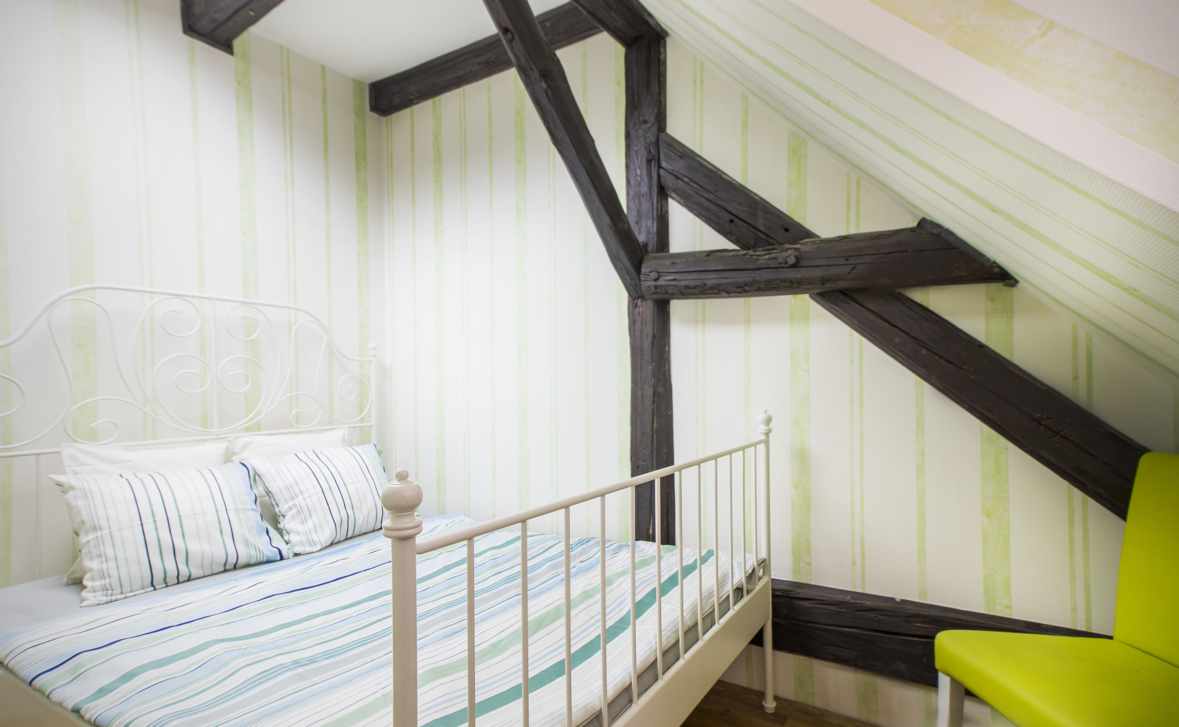 A bedroom with a bed, a chair, and a sloped ceiling.