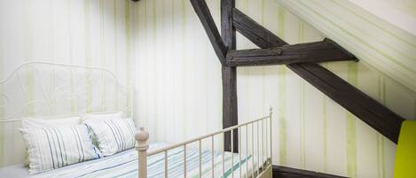 A bedroom with a bed, a chair, and a sloped ceiling.