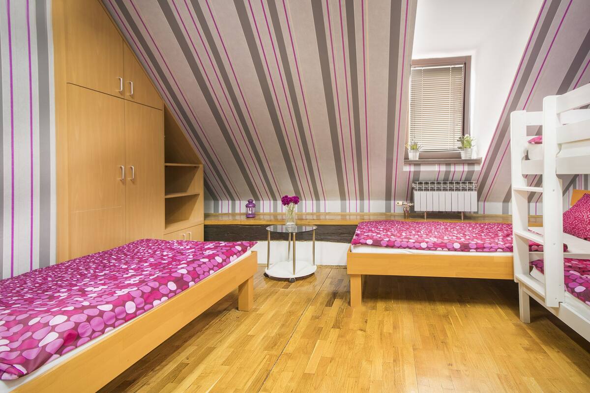 Ein Zimmer mit zwei Etagenbetten, einem Holzschrank und einem kleinen runden Tisch mit einem Blumenstrauß.