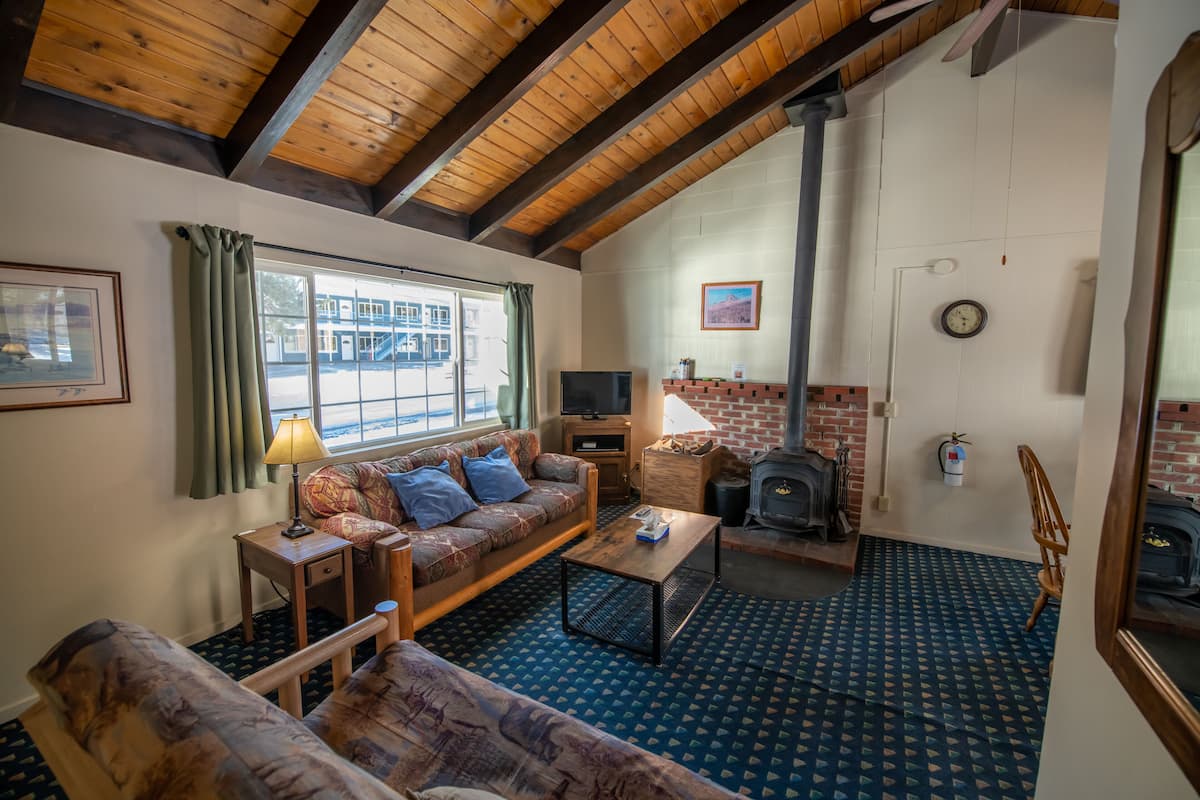 A cozy living room with a sofa, a coffee table, a fireplace, and a television.
