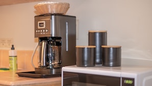 A kitchen with a coffee maker, a microwave, and two stainless steel containers on the counter. - Gull Lake Lodge (June Lake)