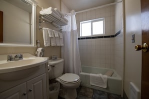 A bathroom with a sink, toilet, bathtub, and a window. - Gull Lake Lodge (June Lake)