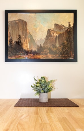 A framed landscape painting on a wall, a potted plant on a brown mat, and a wooden floor. - Gull Lake Lodge (June Lake)