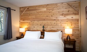 A neatly made bed with white linens, two bedside lamps, and a wooden headboard. - Gull Lake Lodge (June Lake)