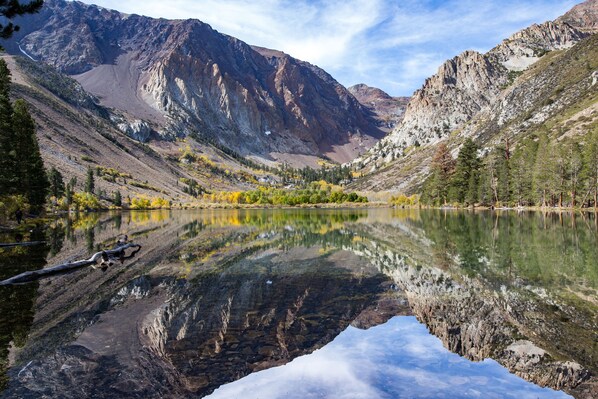 A mountainous landscape with a clear lake reflecting the surrounding scenery. - Gull Lake Lodge (June Lake)