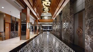 Un moderno vestíbulo de hotel con piso estampado, paneles de madera y paredes de mármol.