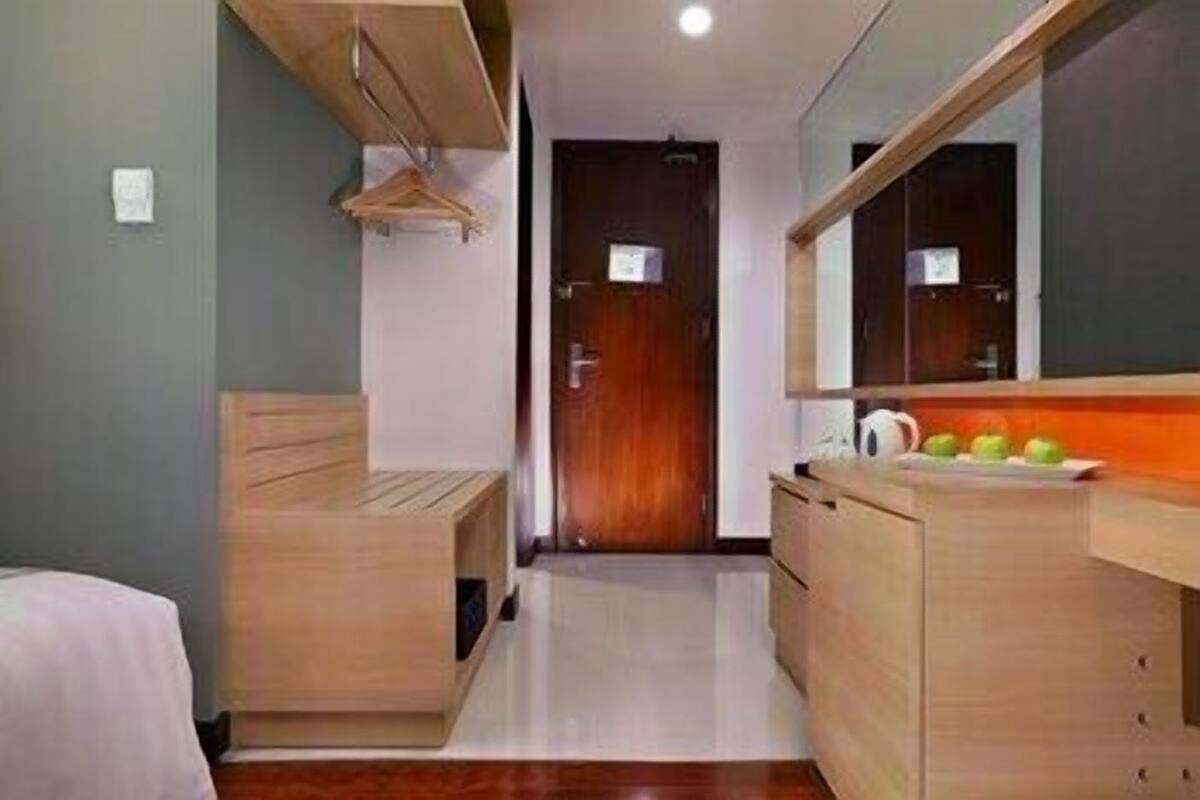 Una habitación con una cama y un aparador de madera, un espejo y una puerta.