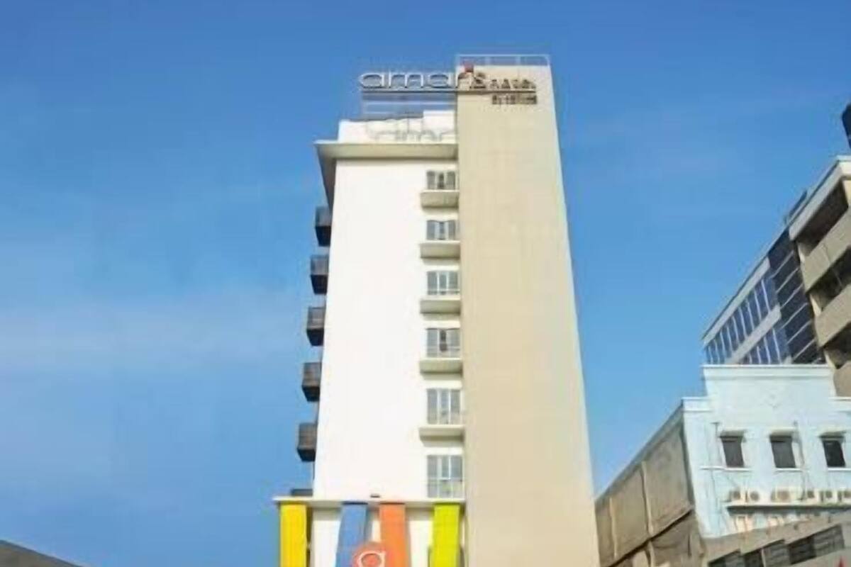 Ein Hotel mit einer vertikalen Fassade, mehreren Etagen und einem Parkplatz mit einigen Autos.