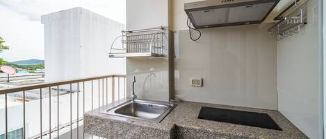 A small kitchen with a granite countertop, a stainless steel sink, a black induction cooktop, and a stainless steel range hood.