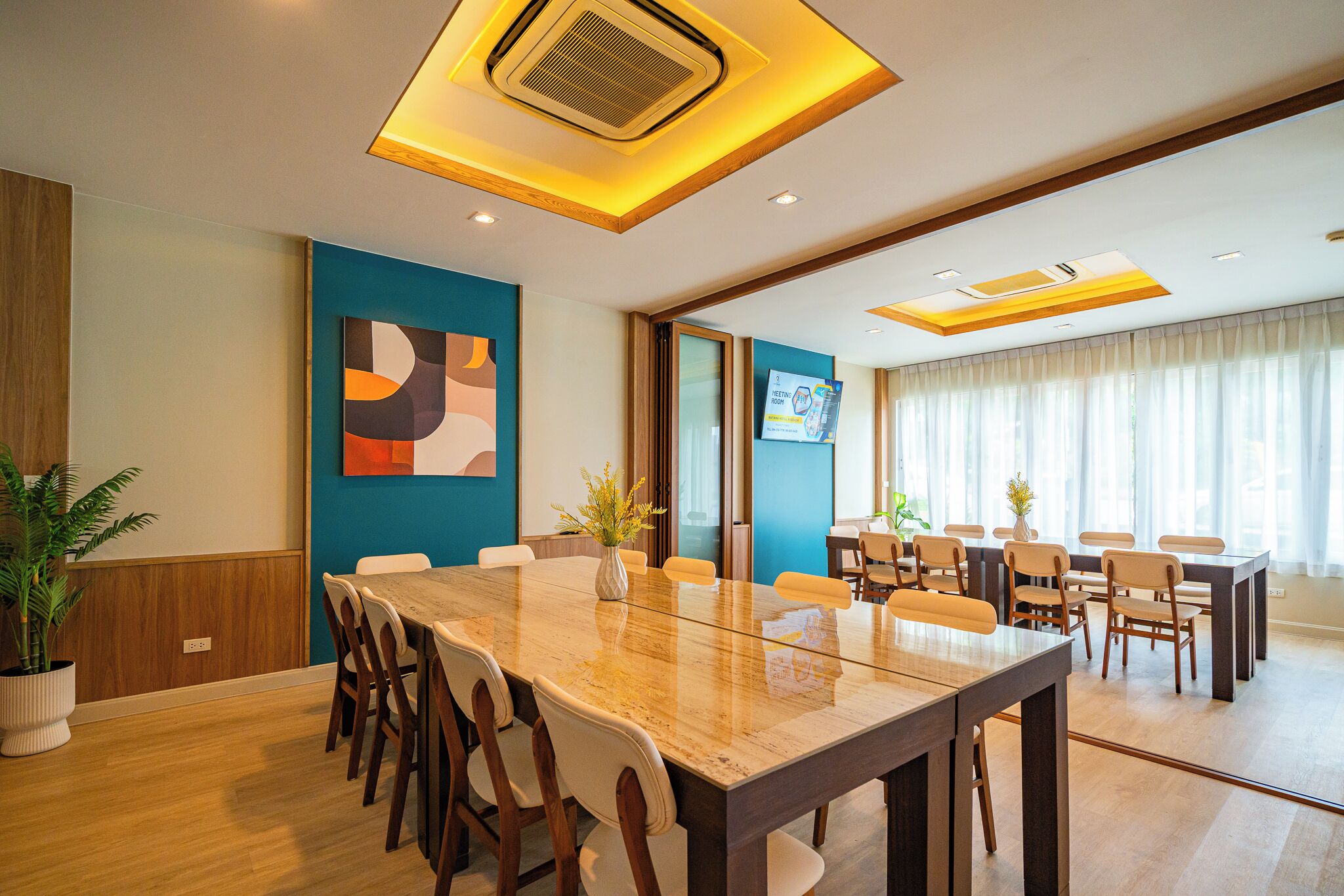 A conference room with a large table, chairs, and a TV screen.