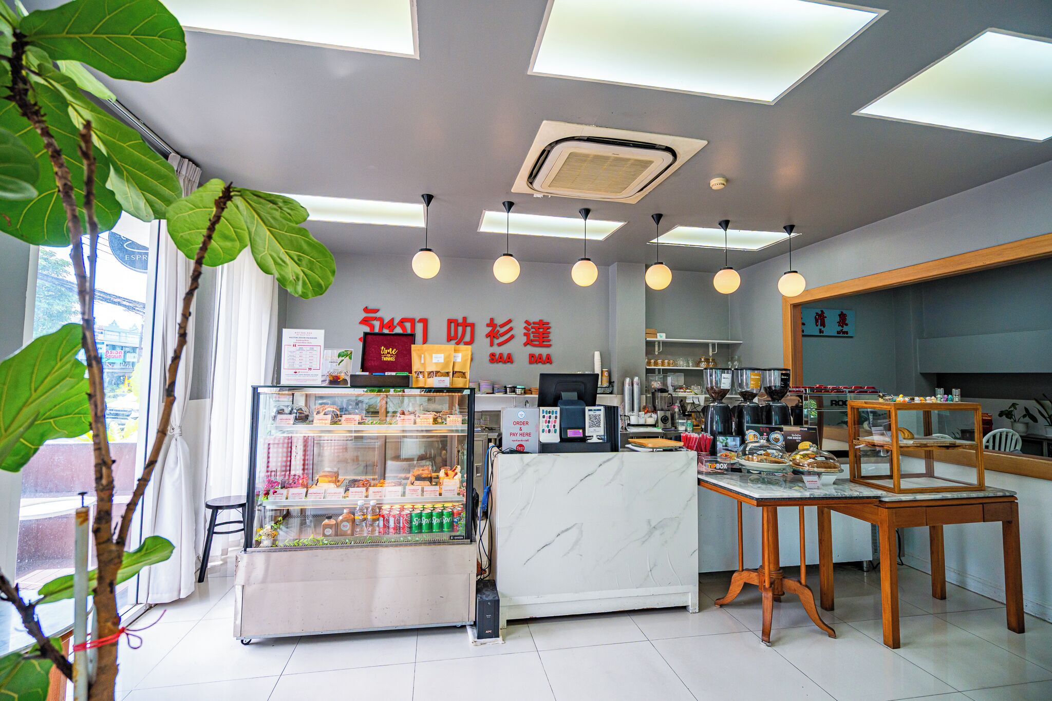 A modern cafe interior with a counter, seating area, and a display case.