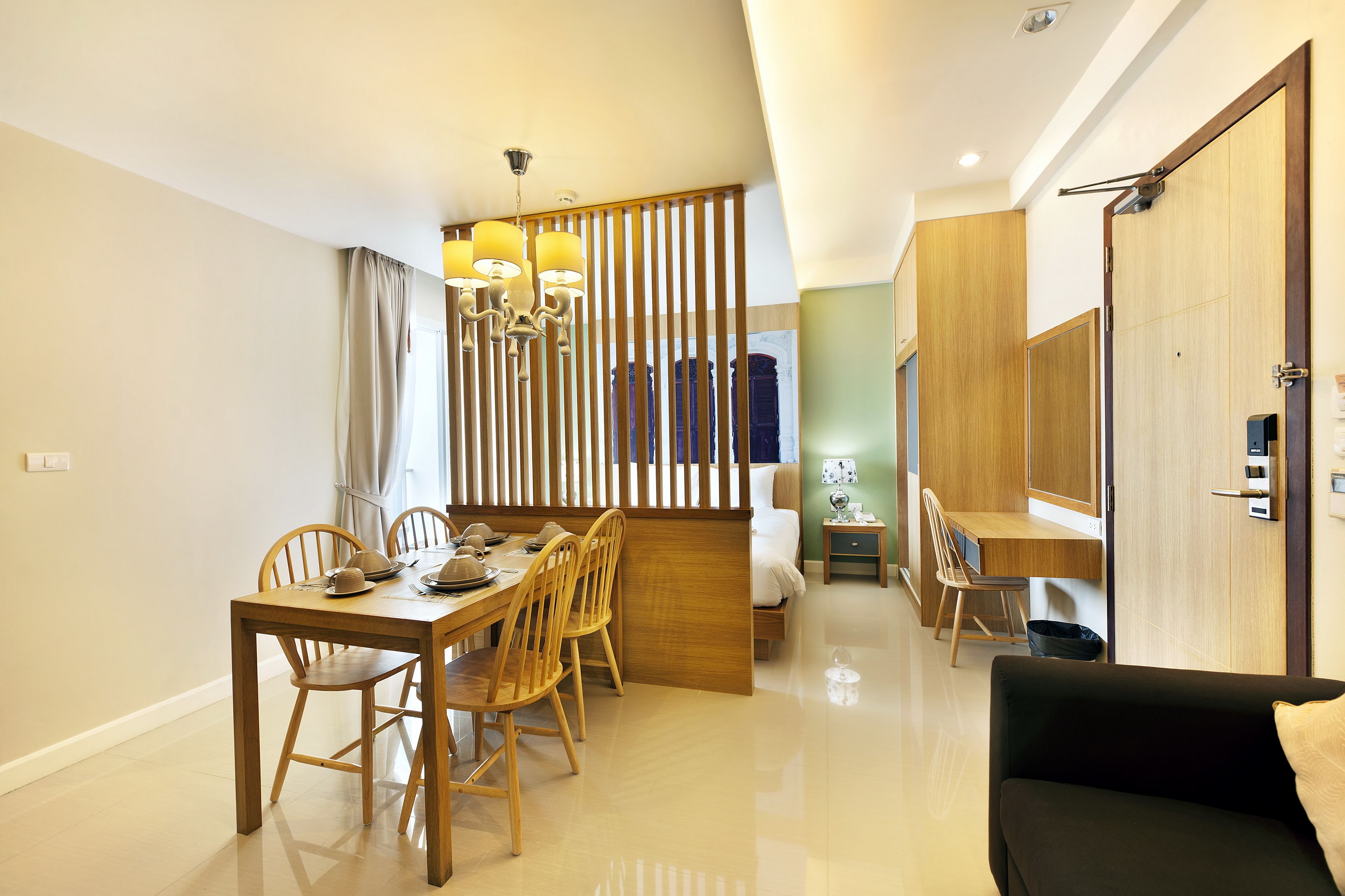 A modern hotel room with a dining area, a sofa, and a wooden partition.